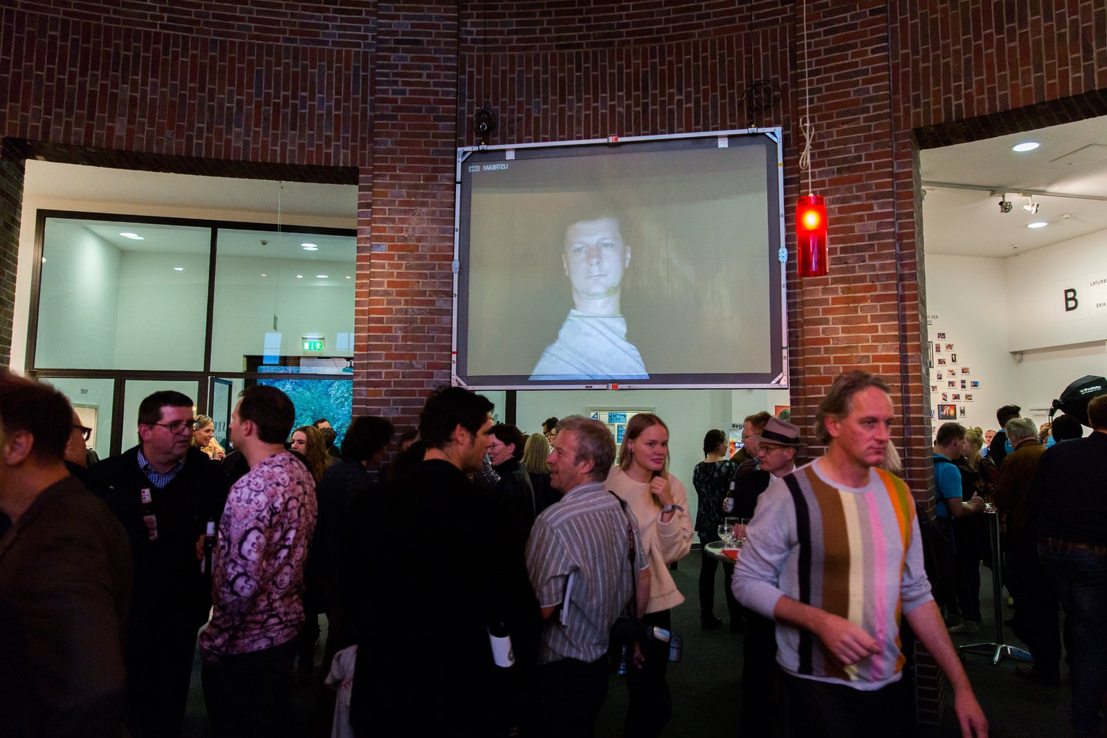 The live-streamed face projected large on a screen above the crowd at the Ego Update opening, NRW-Forum Düsseldorf
