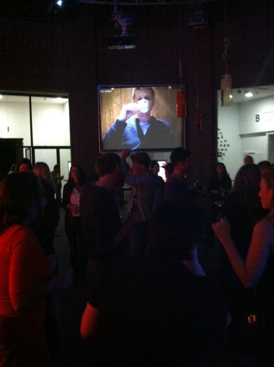 The streamed face drinking from a cup, on the big screen over the opening crowd