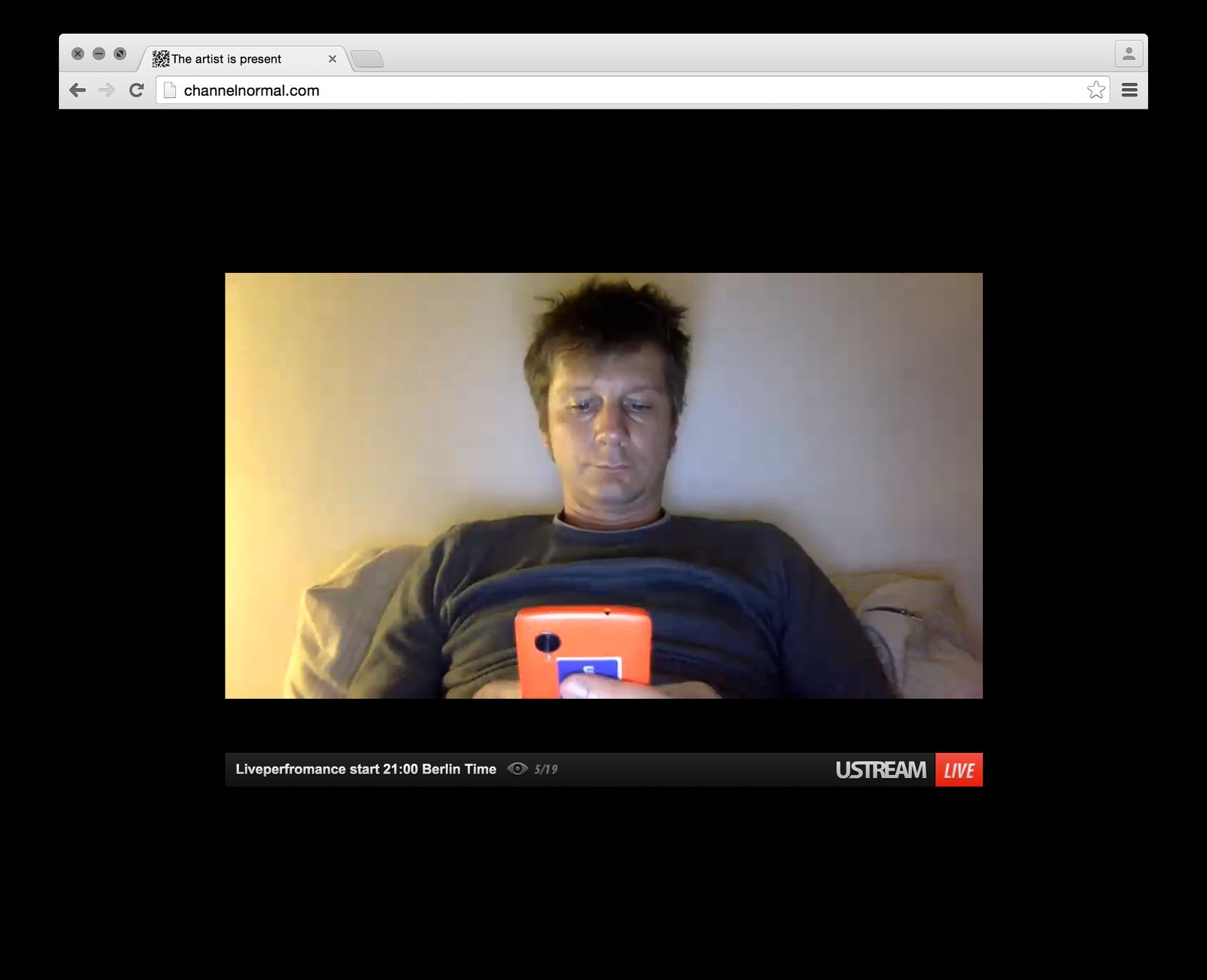 The channel normal live feed — the artist reclining, phone in hand