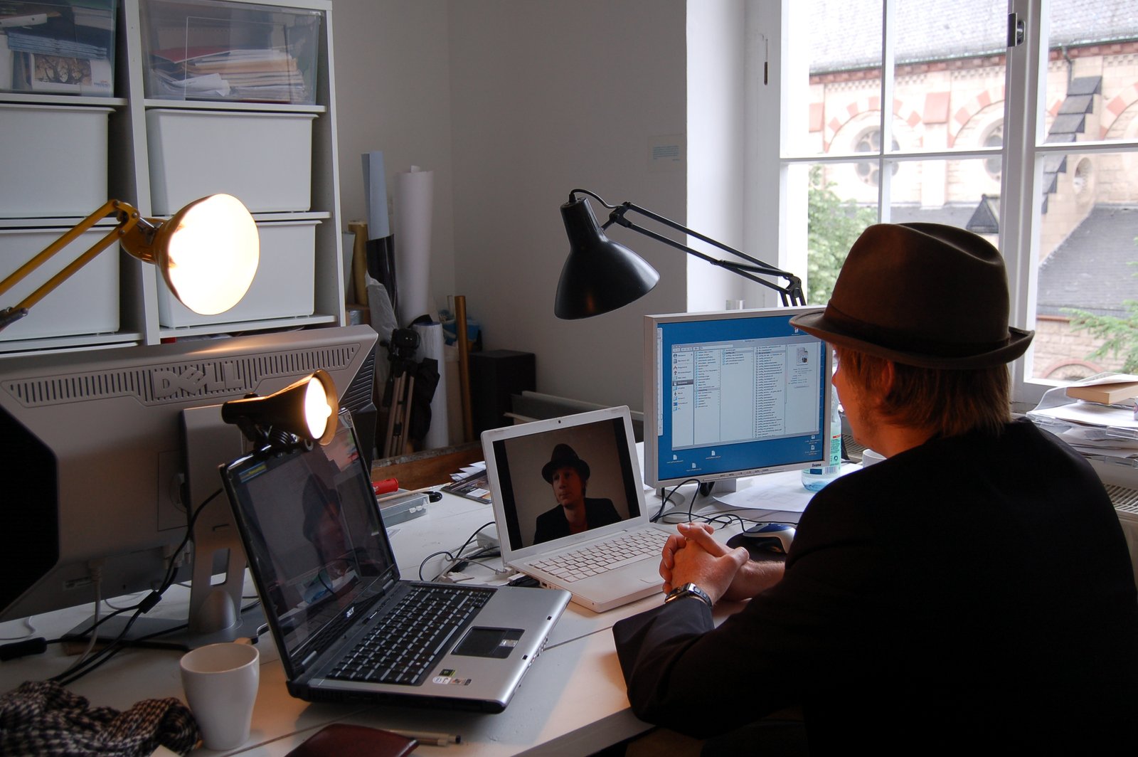 The artist at a desk among monitors and laptops, streaming his image